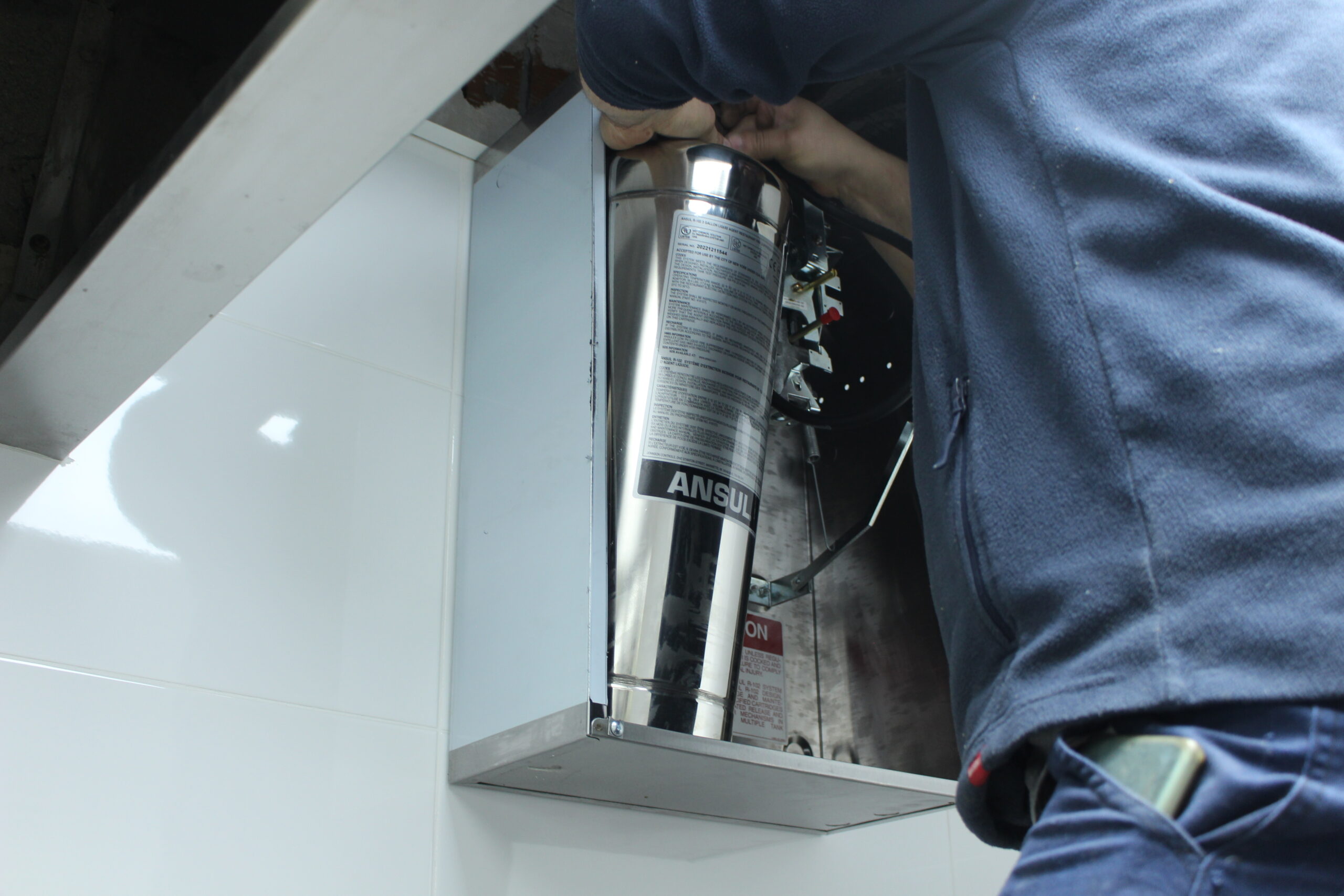 Instalador de Extradai realizando la instalacion de un sistema simple de ansul en una campana de una cocina